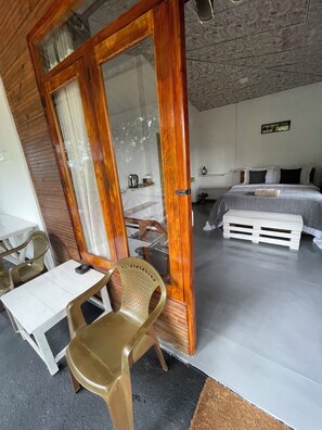 A room with a wooden door, a bed, a bedside table, a chair, and a small table. - Mountain vibe ella (Ella)
