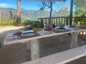 A picnic table set outdoors with plates of food, utensils, and a yellow mug. - Mountain vibe ella (Ella)