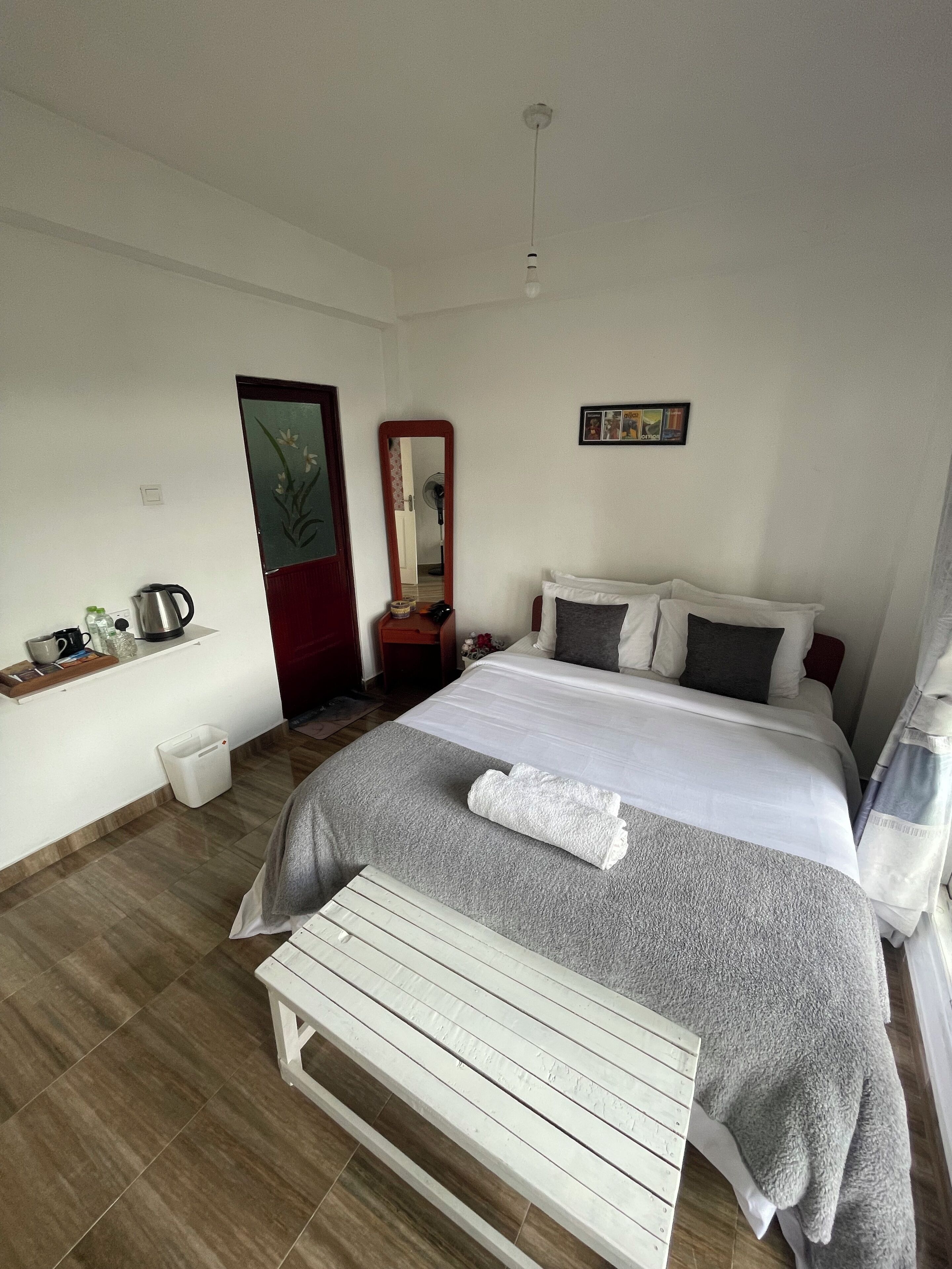 A neatly arranged bedroom with a bed, bedside table, and a mirror.