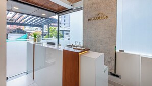 A modern reception area with a wooden reception desk, a glass partition, and a view of the outside. - Treebo De Cloud 9 Regency (Thiruvananthapuram)