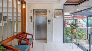 A modern reception area with a staircase, a reception desk, and a large window with a view of the outside. - Treebo De Cloud 9 Regency (Thiruvananthapuram)