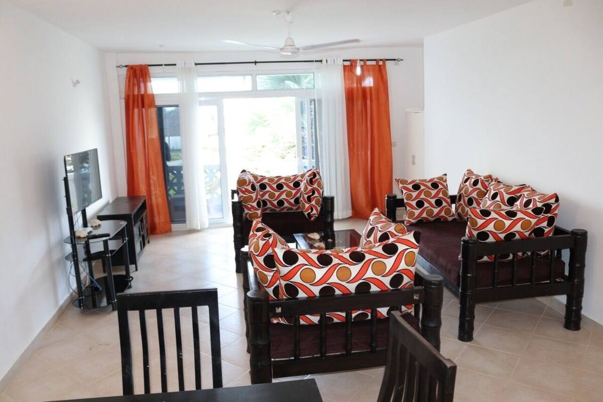 Un salon comprenant un canapé, un téléviseur et une table à manger.