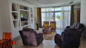 A living room with a fireplace, a television, and a balcony with curtains.