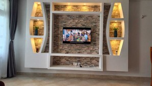 A modern living room with a stone wall TV stand, built-in shelves, and recessed lighting.