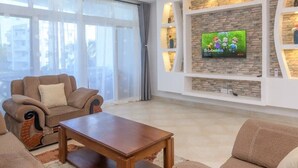 A modern living room with a sofa set, a coffee table, and a TV mounted on a stone wall.