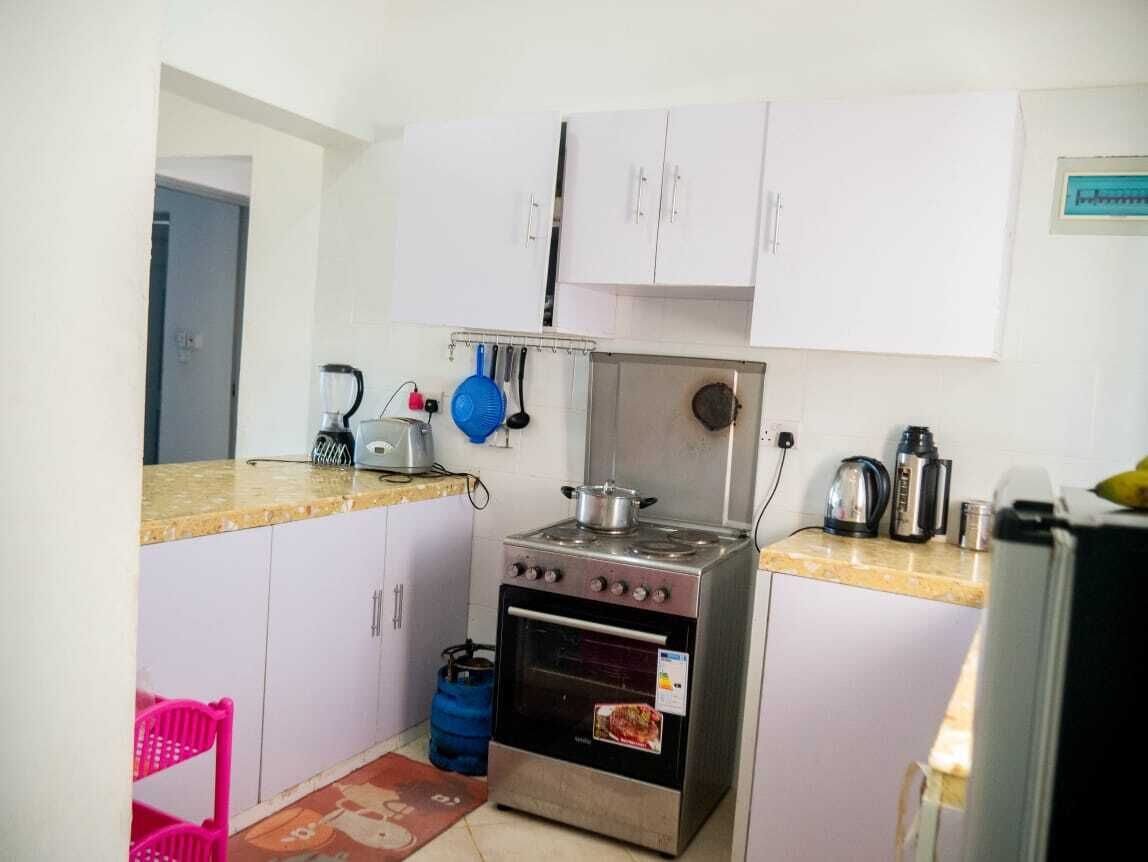 Una cucina compatta con mobili bianchi, un fornello a gas, un forno e un lavandino.