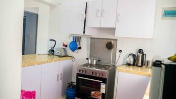 A compact kitchen with white cabinets, a gas stove, an oven, and a sink.