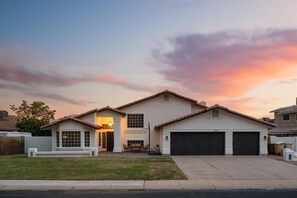 A two-story house with a garage, a front porch with seating, and a well-maintained lawn. - Rock Climbing Wall~Pool& Mini Golf~Game Room~Mural (Peoria)