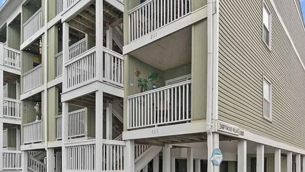 Un edificio de varios pisos con balcones y una zona de estacionamiento techada.