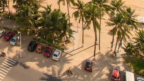 An aerial view of a beach with palm trees, a parking lot, and a clear view of the ocean. -  Oceanus Vien Trieu Nha Trang Apartment - Thai Ha (Bac Nha Trang)