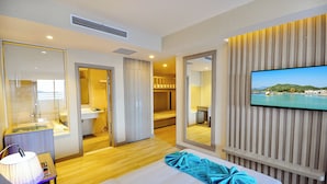 A hotel room with a bed, a TV, a bathroom, and a view of a coastal landscape. -  Oceanus Vien Trieu Nha Trang Apartment - Thai Ha (Bac Nha Trang)