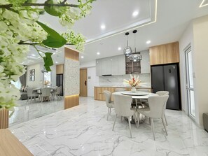 A modern kitchen with a marble countertop, wooden cabinets, and a black refrigerator. -  Oceanus Vien Trieu Nha Trang Apartment - Thai Ha (Bac Nha Trang)