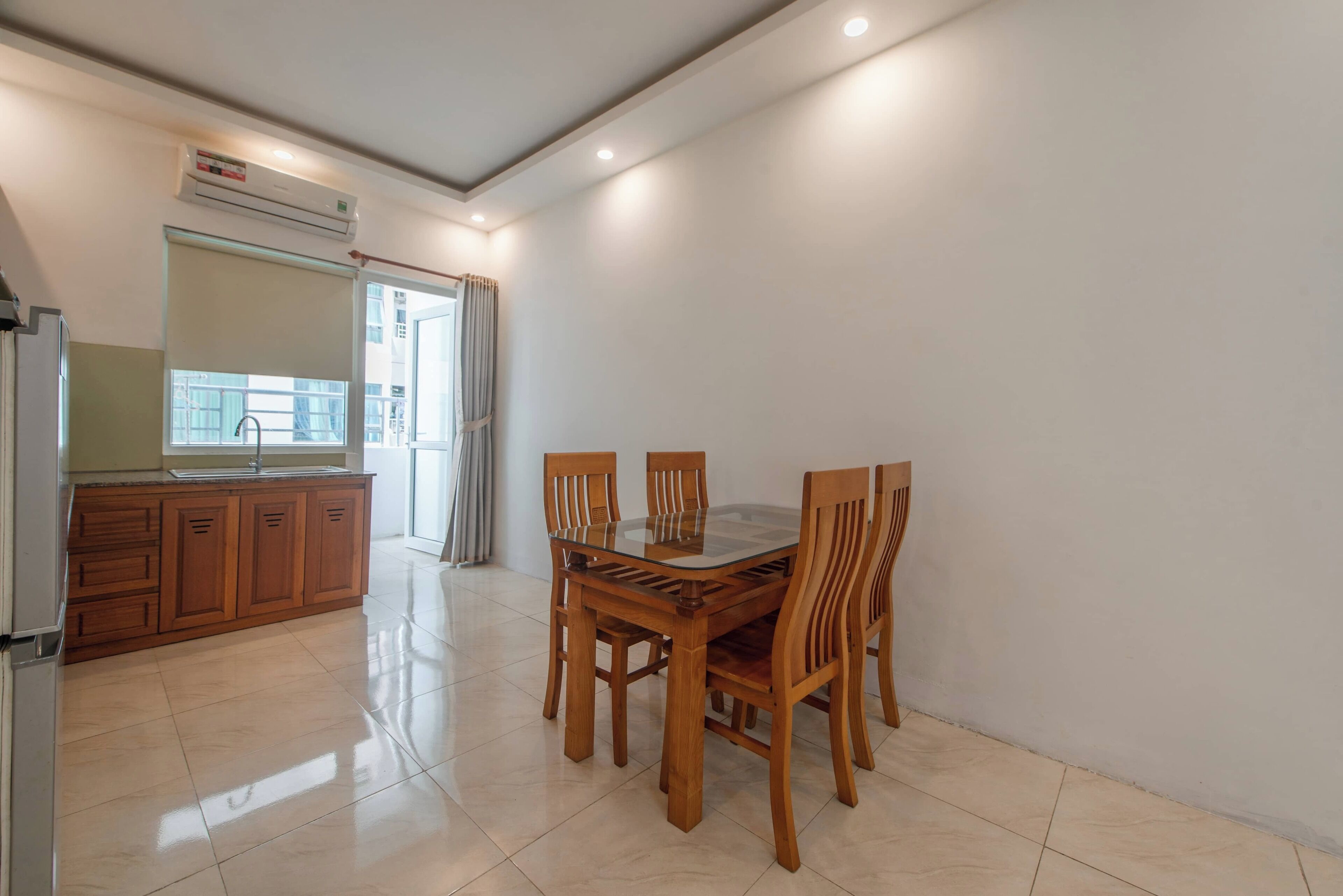A modern kitchen with wooden cabinets, a glass dining table, and chairs.