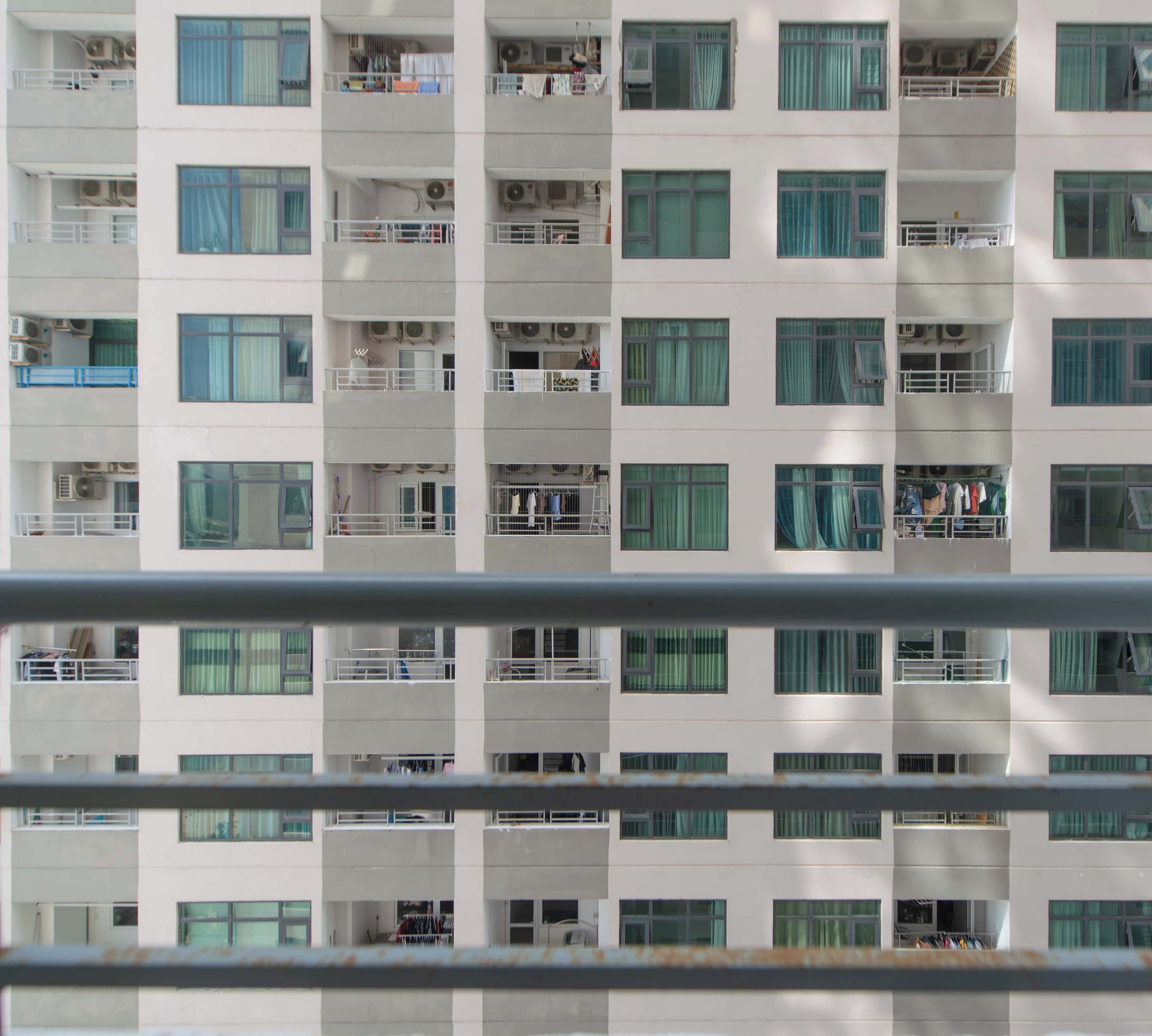 A multi-story residential building with balconies, air conditioning units, and visible laundry hanging outside.