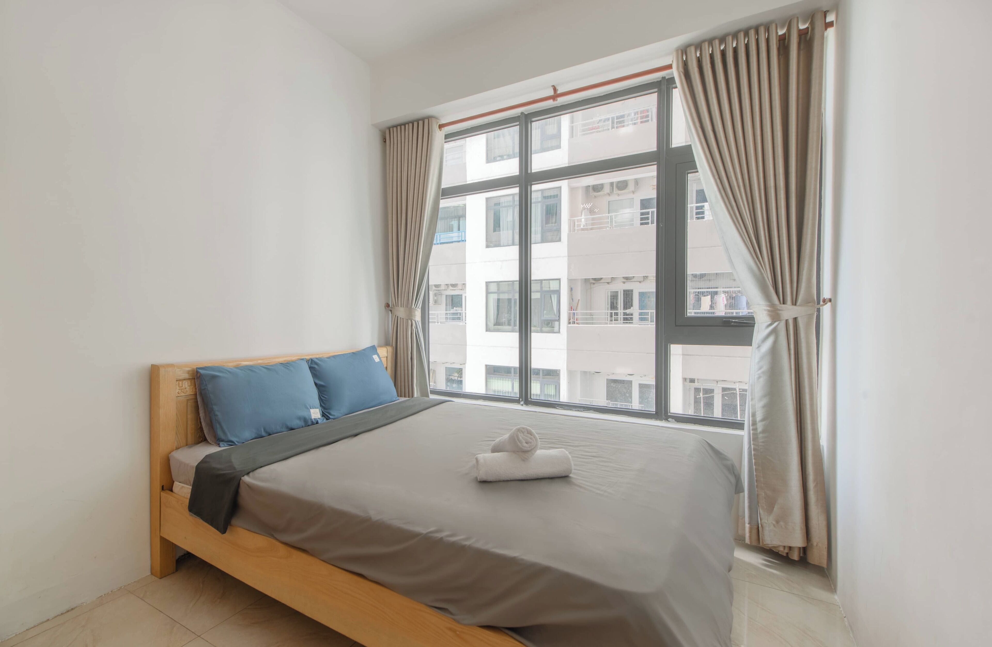 A bedroom with a bed, a window, and curtains.