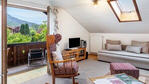 A cozy living room with a sofa, a television, and a rocking chair. - Apartment 'Ferienwohnung Haus Greif' with Mountain View, Balcony and Wi-Fi (Garmisch-Partenkirchen)
