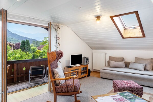 A cozy living room with a sofa, a television, and a rocking chair.