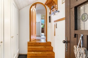 Un escalier en bois mène à une pièce dotée d’une porte, d’une fenêtre et d’un porte-manteau fixé au mur.