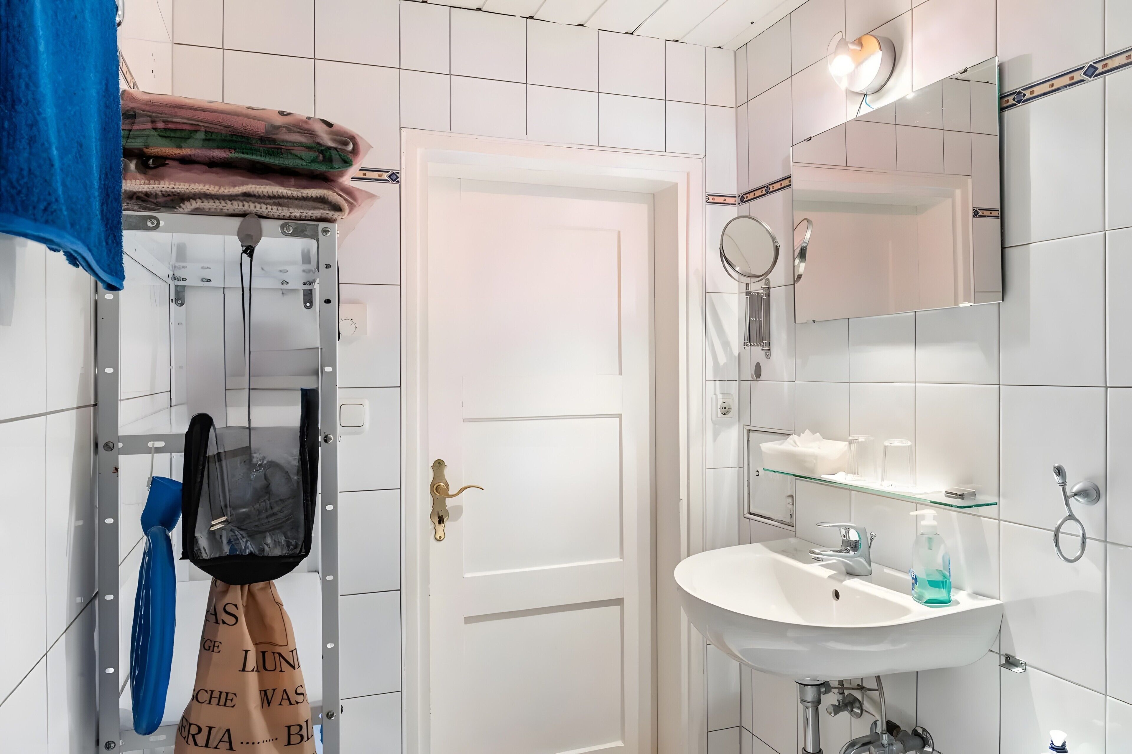 Baño con lavamanos blanco, espejo y toallero.