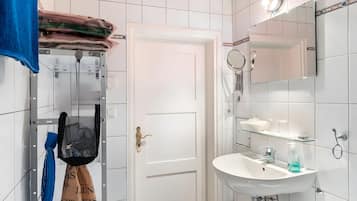 Baño con lavamanos blanco, espejo y toallero.