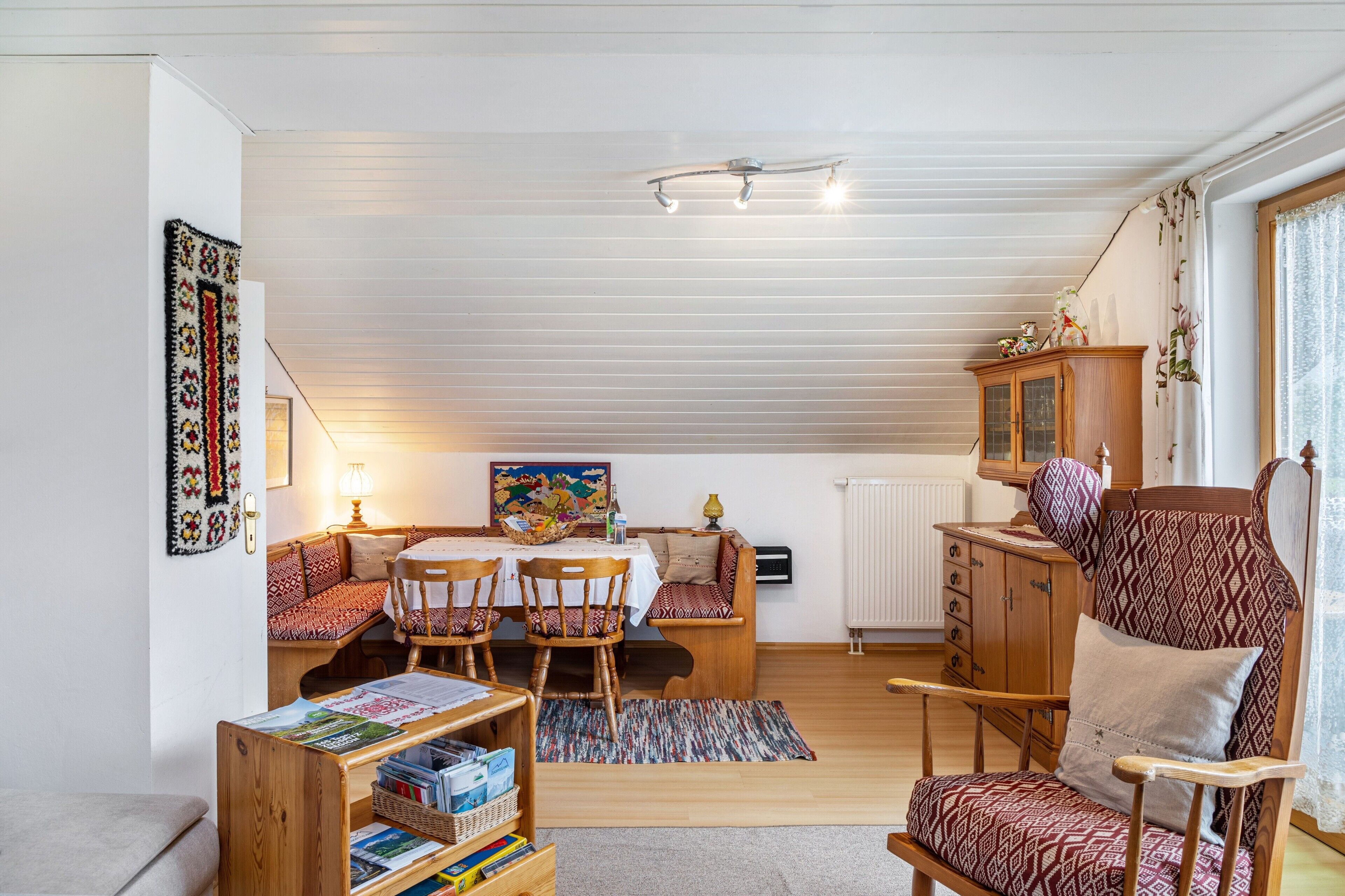 Een gezellige woonkamer met een eethoek, houten meubels, een radiator en een plafondventilator.