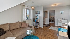 A modern living room with a sofa, a glass coffee table, and a dining area in the background. - Apartment 'Ferienwohnung Hobmaier' with Mountain View, Shared Garden and Wi-Fi (Forstern)