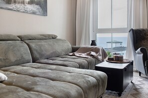 Una sala de estar con un sofá modular, una mesita auxiliar y vistas a través de una ventana.