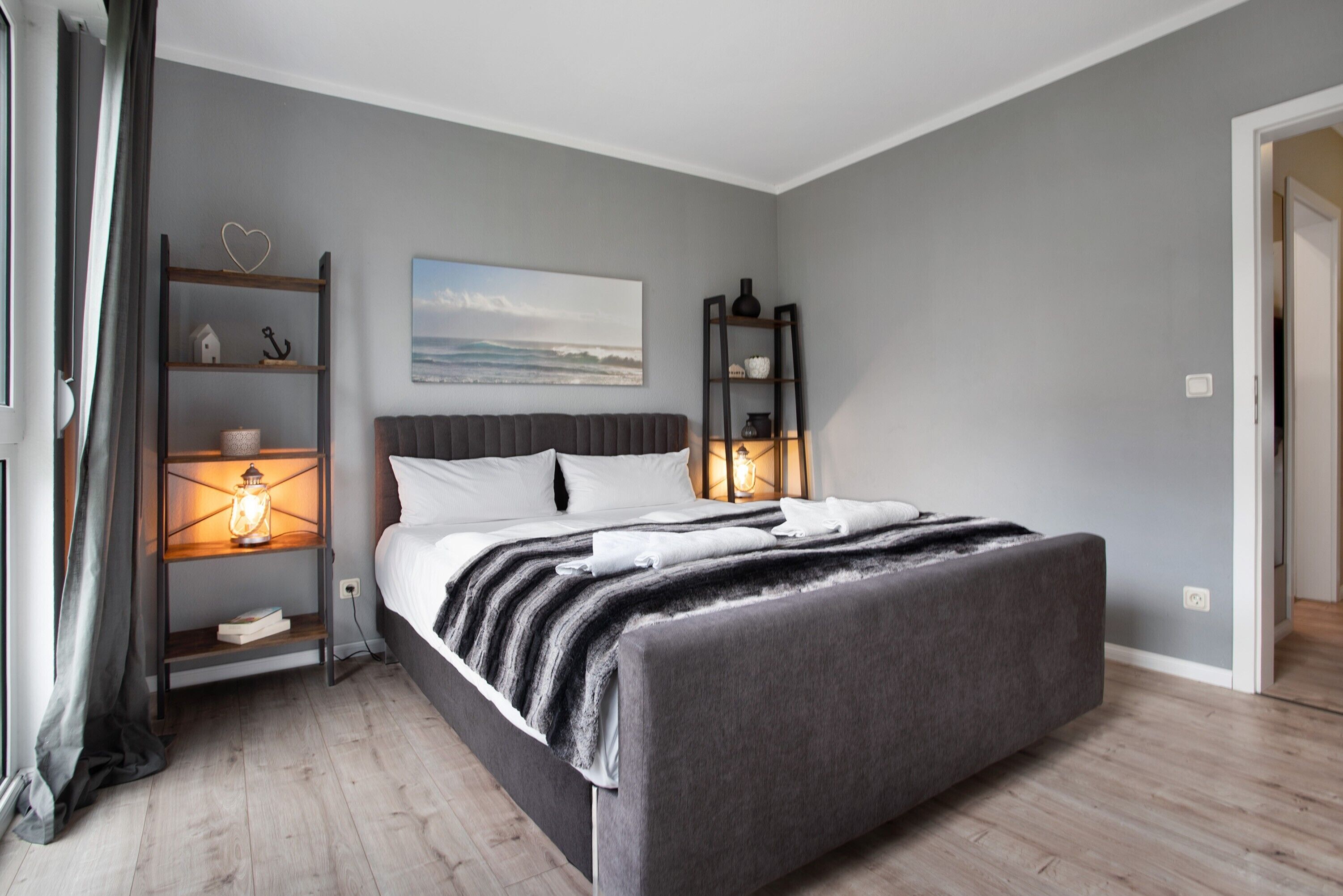 Ein modernes Schlafzimmer mit einem großen Bett, Einbauschränken, einem Gemälde und einem Nachttisch mit Lampe.