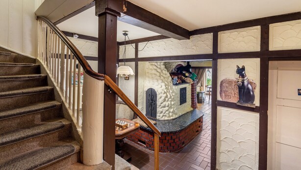 A staircase with a wooden handrail and carpeted steps leading to a room with a fireplace, a small table with a chessboard, and a decorative dog statue.