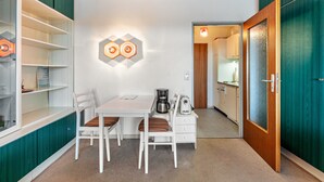 Cocina compacta con comedor, armarios blancos y cafetera.