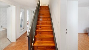 A staircase with wooden steps and a metal railing, leading to a room with white walls and a door.