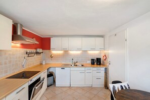 Une cuisine compacte avec des meubles blancs, un four encastré, un lave-vaisselle et un plan de travail doté d’un évier.
