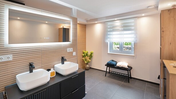 A modern bathroom with two sinks, a large mirror, and a bench. - "Antilope" Apartment in Würmtal with Terrace, Wi-Fi, and Air Conditioning (Gräfelfing)