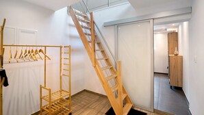 A room with a wooden staircase, a drying rack, and a sliding door leading to another area. - "Antilope" Apartment in Würmtal with Terrace, Wi-Fi, and Air Conditioning (Gräfelfing)