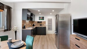 A modern kitchen with a refrigerator, a dining table with chairs, and a TV. - "Antilope" Apartment in Würmtal with Terrace, Wi-Fi, and Air Conditioning (Gräfelfing)