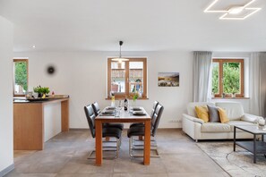 A modern kitchen with a dining area, a sofa, and a coffee table. - Apartment "Falkenstein" with Mountain View, Two Balconies, Private Sauna (Garmisch-Partenkirchen)