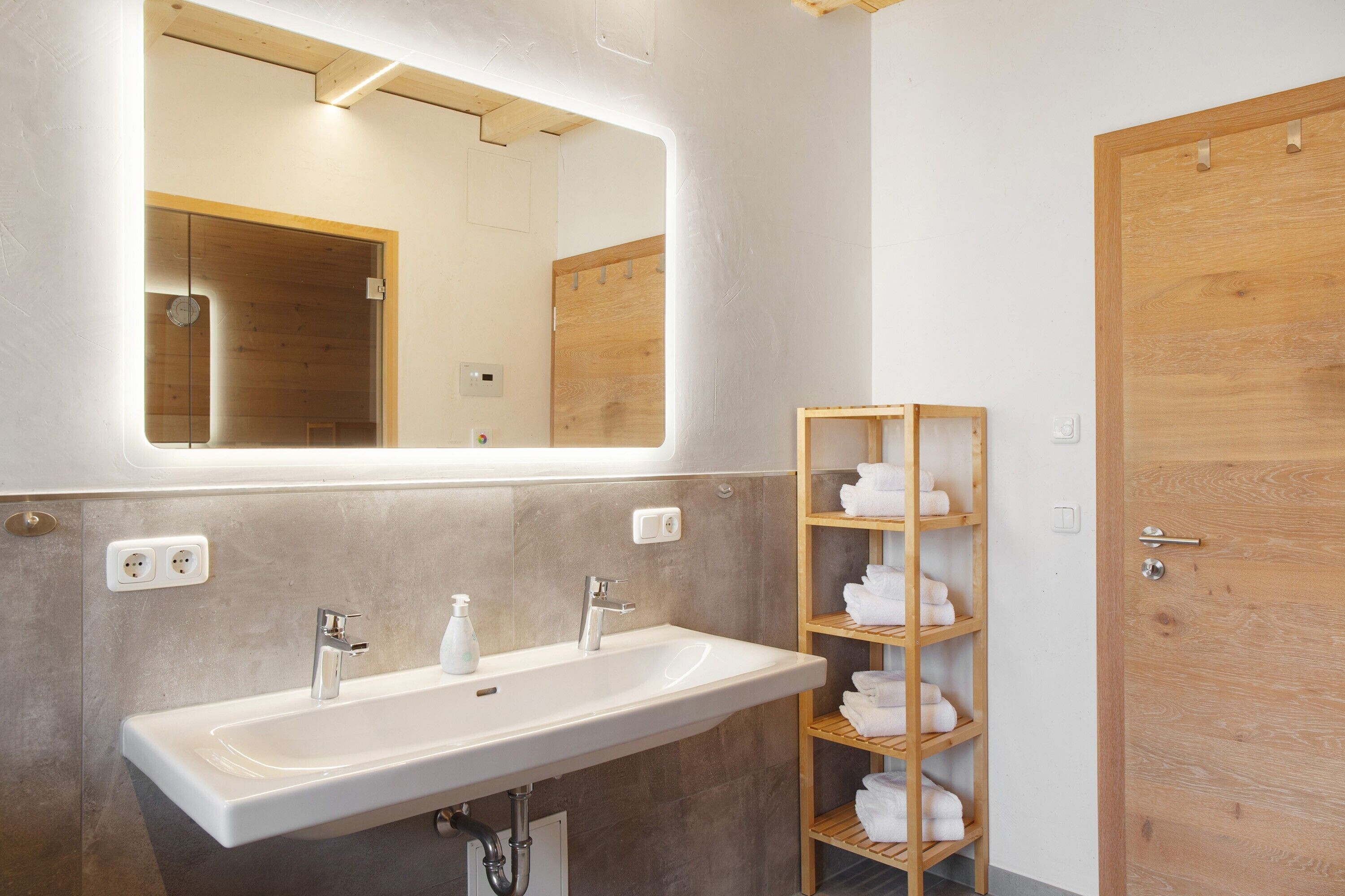 A bathroom with a white sink, a mirror, and a wooden towel rack.