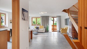 A spacious living area with a sofa, armchairs, a coffee table, and a staircase. - Falkenstein Apartment with Mountain View, Two Balconies, Private Sauna (Garmisch-Partenkirchen)
