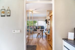 Une pièce avec un plancher en bois, une table ronde, un canapé et un téléviseur posé sur un meuble en bois.
