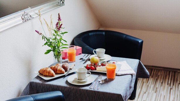 A breakfast table with croissants, fruit, juice, and a vase of flowers. - Apartment 'Hexe I - Mit Blick Auf Den Wurmberg' with Mountain View, Balcony and Wi-Fi (Braunlage)