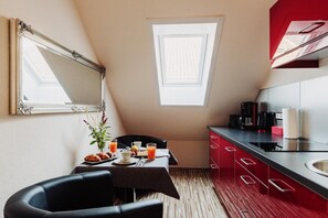 Eine kleine Küchenzeile mit einem roten Schrank, einer Kaffeemaschine und einem Fenster.