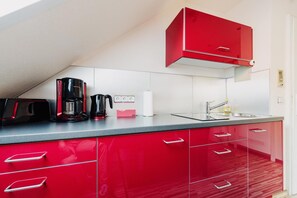 A kitchen with red cabinets, a coffee maker, a toaster, and a sink.