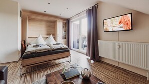 A modern bedroom with a bed, a television, a radiator, and a view of the outdoors. - Apartment 'Hexe I - Mit Blick Auf Den Wurmberg' with Mountain View, Balcony and Wi-Fi (Braunlage)