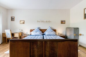 Une chambre à coucher avec un lit en bois, un bureau, une chaise et un mur orné d’un panneau décoratif.