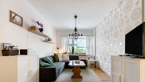 Ein Wohnzimmer mit einer Couch, einem Couchtisch, einem Fernseher und einem Bücherregal.