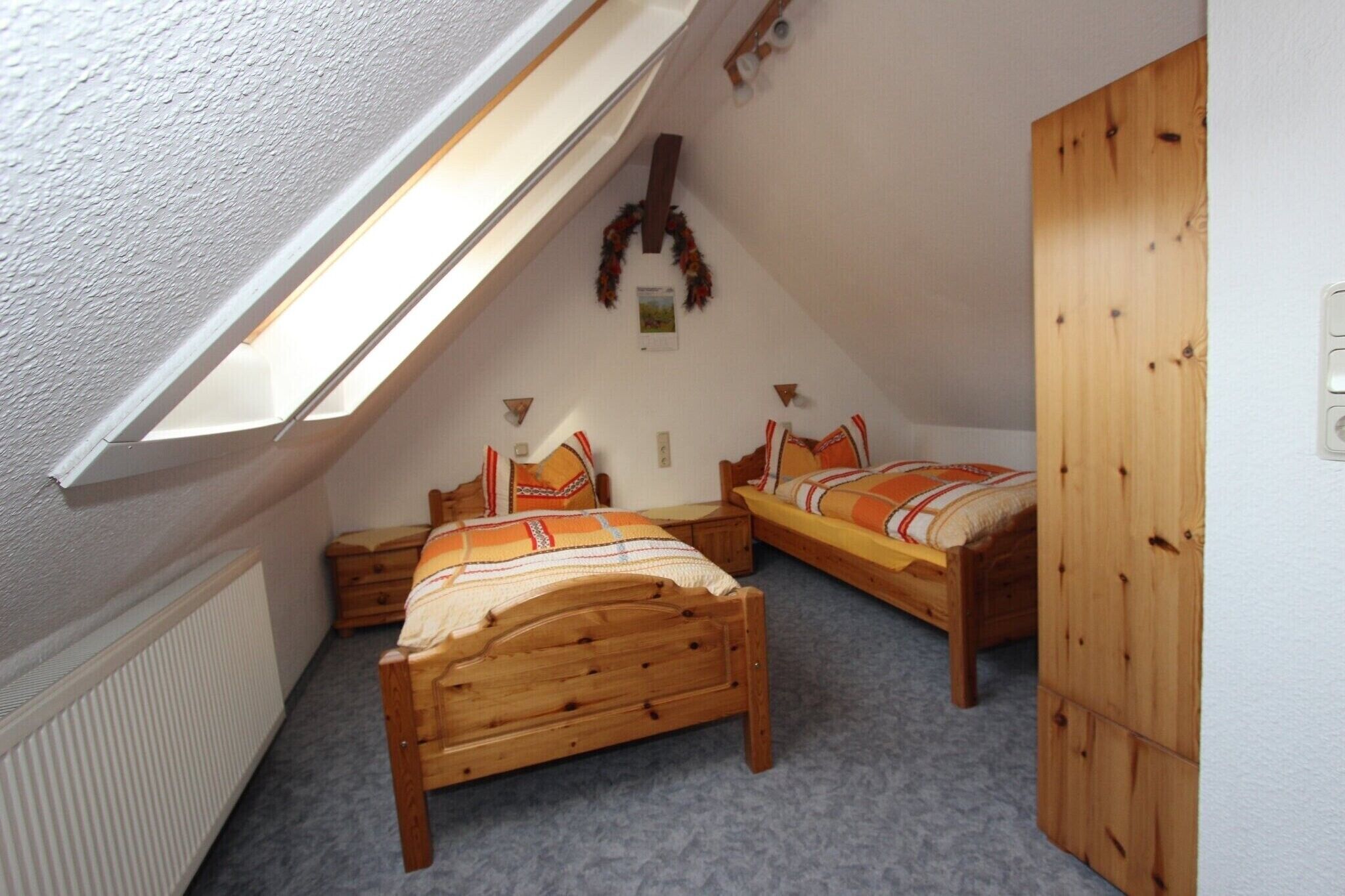 A small attic bedroom with two wooden beds, a sloped ceiling, and a radiator.