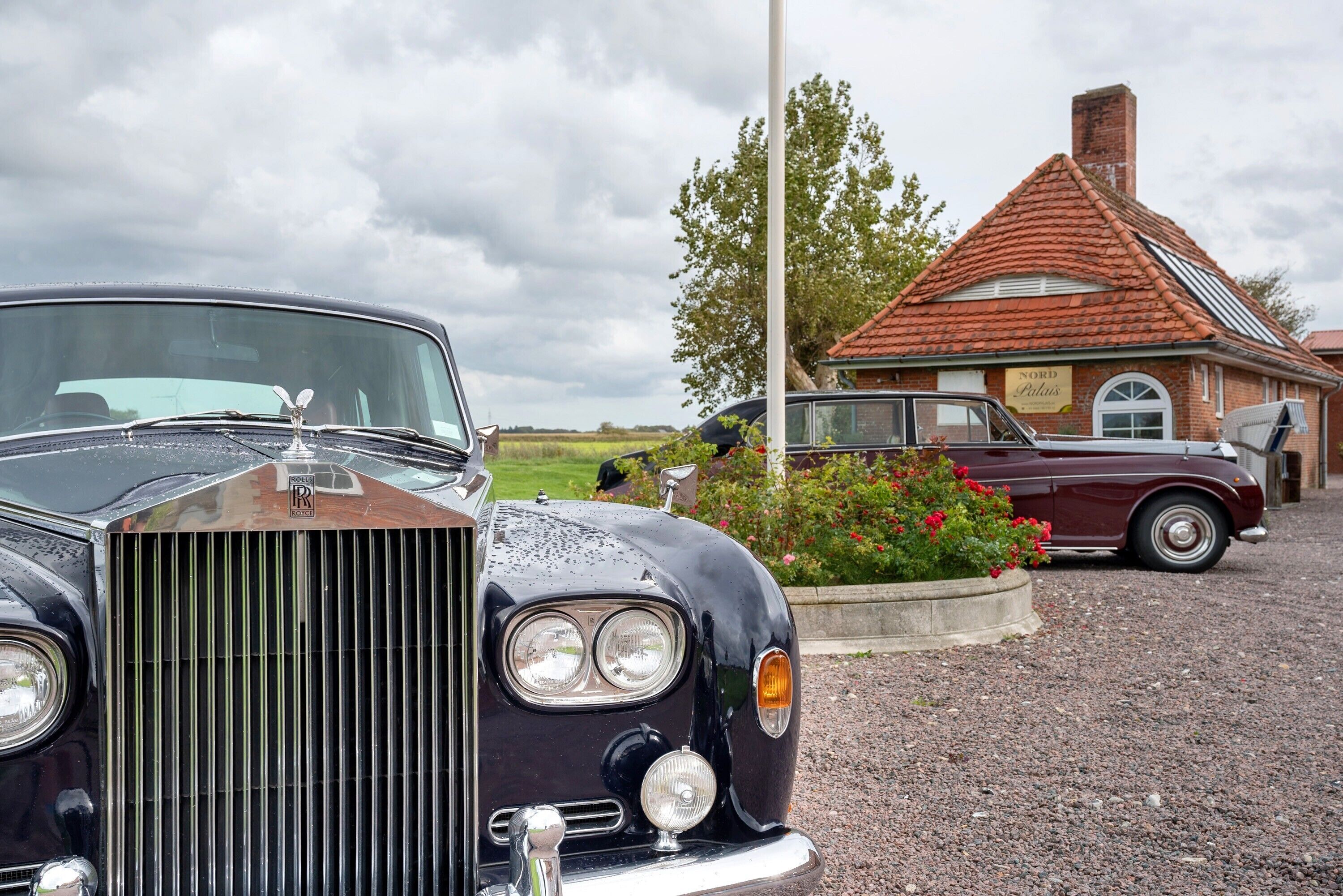 A classic car parked in front of a building with a sign that reads 'Nord Pilatus.'