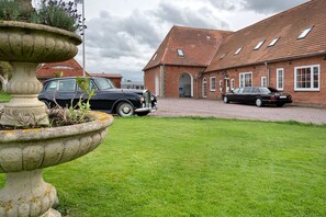 A building with a brick facade, a stone fountain, and two parked cars.