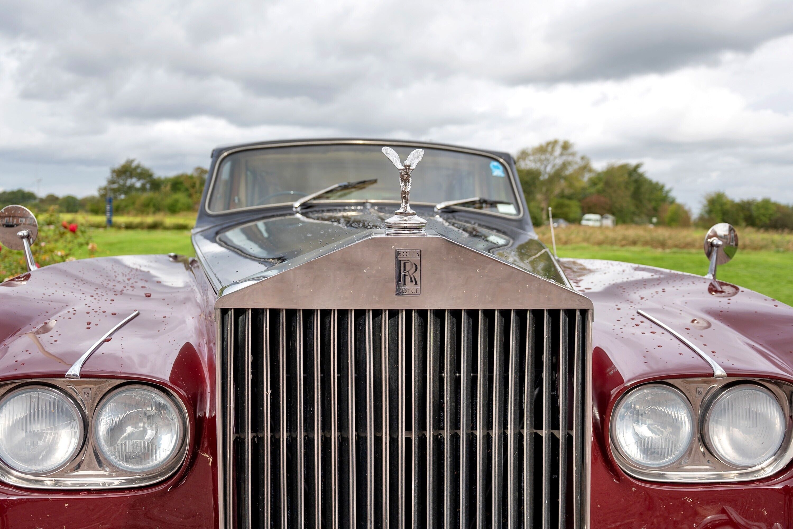 A classic car with a prominent grille and emblem, parked outdoors.