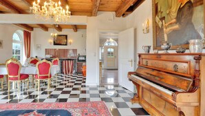 Un comedor con piso a cuadros, un piano y una araña.